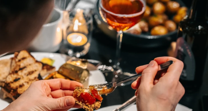 Person äter ost, kex och marmelad.