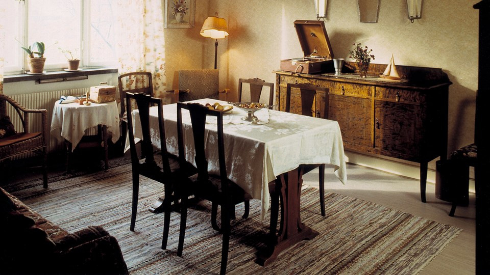 Vardagsrum med matsalsbord, stolar, utdragssoffa och fåtöljer.