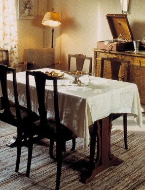 Vardagsrum med matsalsbord, stolar, utdragssoffa och fåtöljer.
