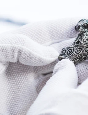 Händer med vita handskar som håller en torshammare.