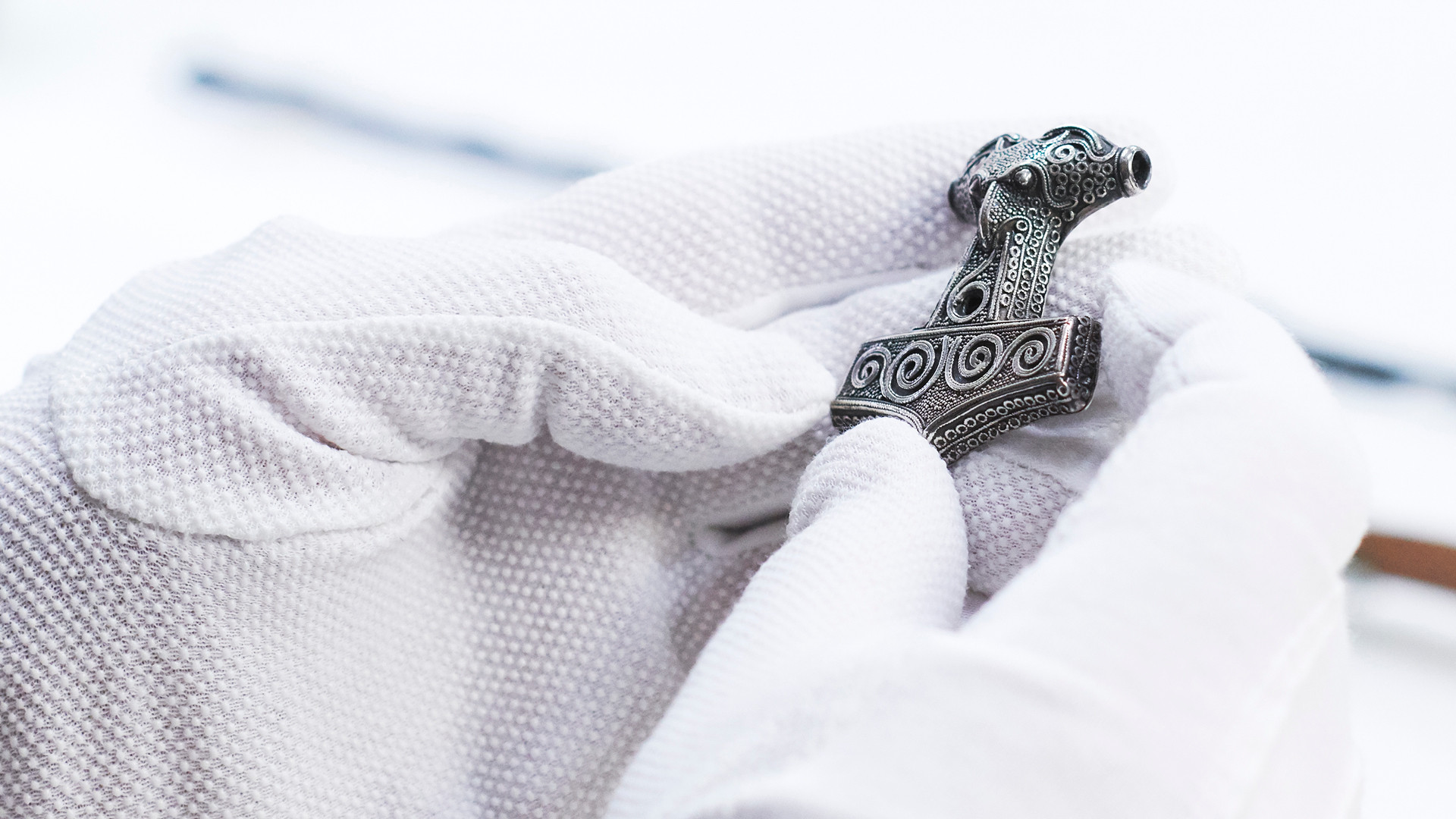 Händer med vita handskar som håller en torshammare.