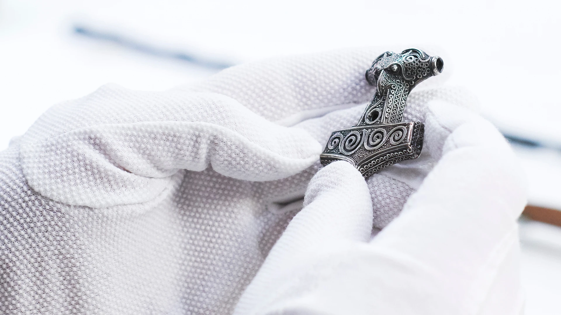 Händer med vita handskar som håller en torshammare.