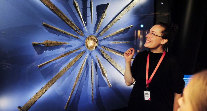 Guide berättar för besökare framför utställning om vikingatiden
