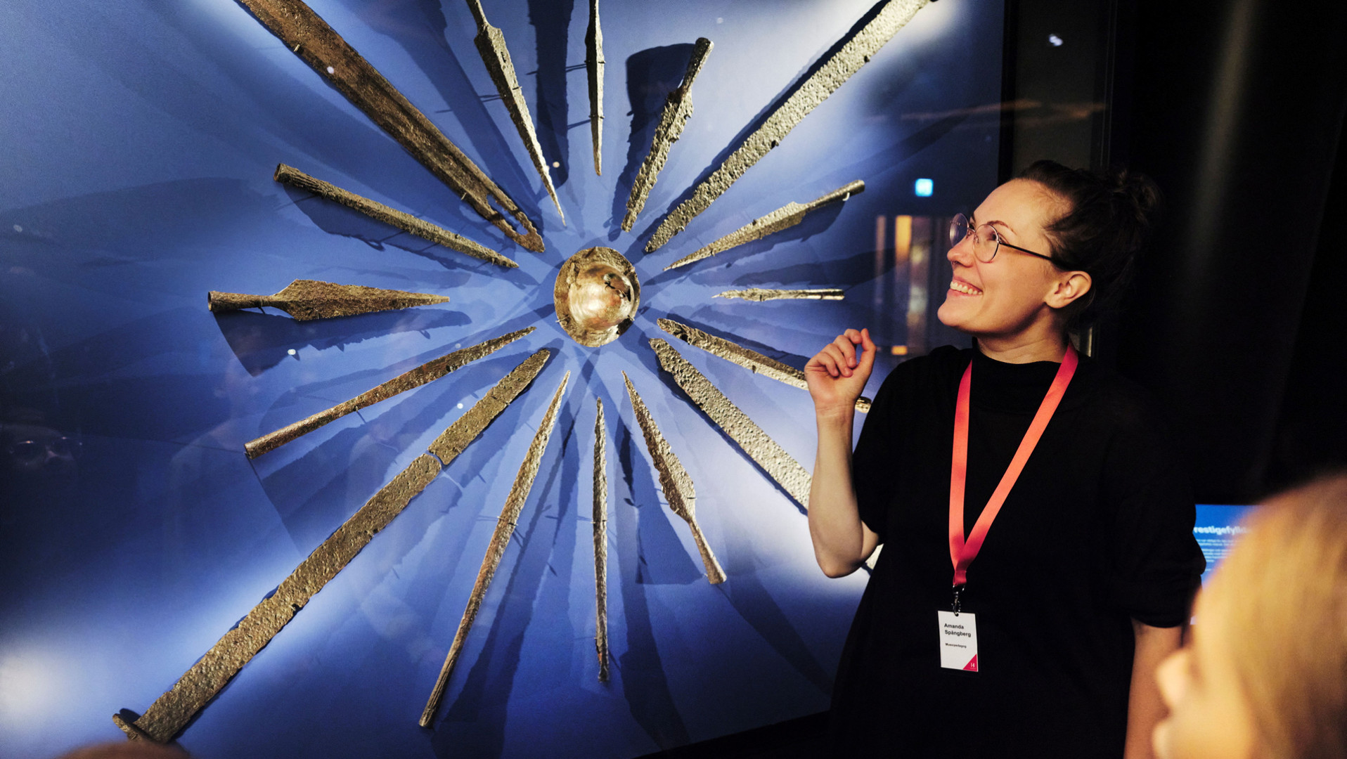 Guide berättar för besökare framför utställning om vikingatiden