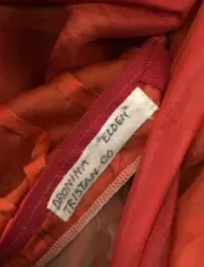Detalj av kostym i rött tyg med en namnlapp.