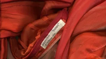 Detalj av kostym i rött tyg med en namnlapp.