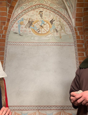 En man och en kvinna i medeltida kläder i en medeltida kyrkobyggnad.
