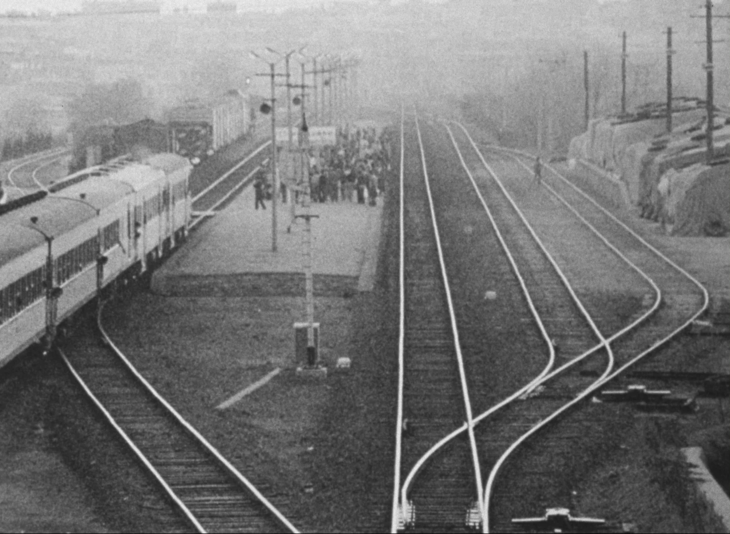 En svartvit bild från en tågstation med tjock dimma.