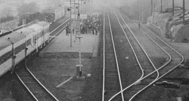 En svartvit bild från en tågstation med tjock dimma.